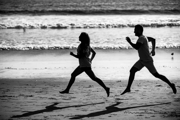 若い男と女が海に沿ってジョギングを実行しています ビーチを走るカップル — ストック写真