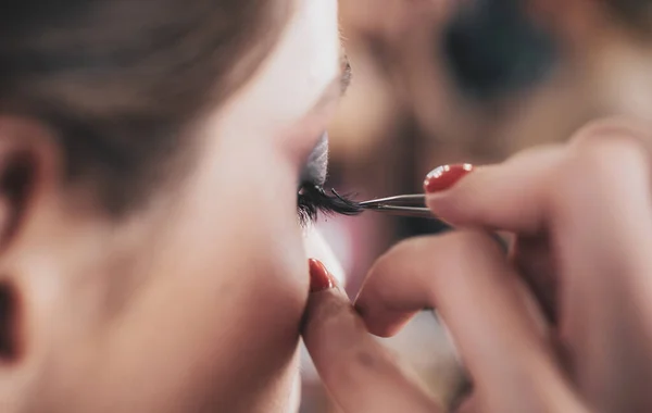 女性美的容貌概念 漂亮的女人和完美的化妆 工作室里的一位专业化妆画家正在画睫毛模型 — 图库照片