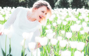 Beyaz laleler arasında gülümseyen bir kız. Renkli parlak kırmızı laleler tarlası