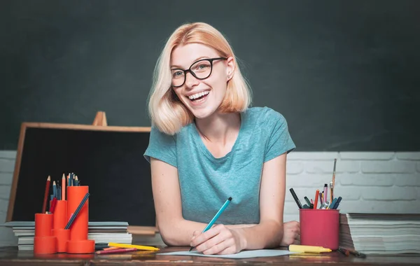 Teacher is skilled leader. Young teacher in glasses over green chalkboard background. Beautiful teacher in classroom. Student studying in the classroom. World teachers day