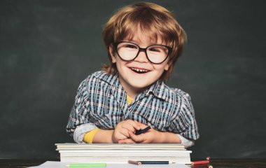 Okula ve mutlu zamanlara geri dönelim. Tahta arka planüzerinde gözlüklü komik küçük çocuk. Bir kitap ile Çocuk