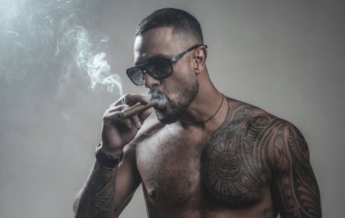 atletik vücutile kaslı maço adam. dövme adam seksi abs. spor ve fitness, sağlık. güven karizması. acımasız sporcu gövde. Steroid. Sigara içiyor. duman üfler. kötü alışkanlık. Zararlı.