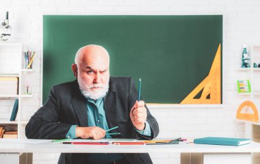 Son sınıf pedagog çalışması. Ders çalışmak eğlencelidir. Bilgi ve eğitim okulu konsepti. Büyükbaba öğretmen okulda karatahtanın yanında.