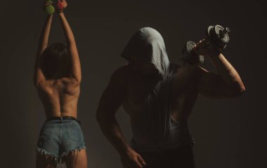 Siyah stüdyo arka planında dambılları olan seksi bir çift.