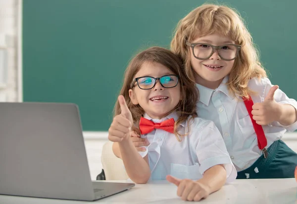 Back to school. Portrait of two happy school kids studying in classroom at elementary school, school children embracing and cheerfully smiling