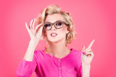 Yakın plan portresi pembe arka planda gözlüklü seksi sarışın kadın. Şaşırmış, ağzı açık bir kadının portresini yakından çek.