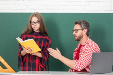 İlkokul sınıfı. Sınıfta öğretmen ve öğrenci. Öğretmen, genç öğrencilere okulda ödev yazma ve okuma konusunda yardım ediyor.