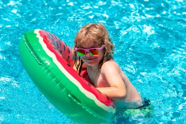 Çocuk oyuncakları. Çocuklar tropikal tatil köylerinde oynarlar. Tatlı komik çocuk, yüzme havuzunda oyuncak yüzme yüzüğüyle rahatlıyor. Yaz tatilinde tropik bir tatil köyünde eğleniyor.