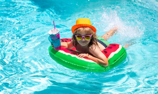 Kids summer vacation, swimming and relax. Cute funny child boy relaxing with toy swimming ring in a swim pool having fun during summer vacation in a tropical resort