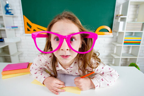Funny child school girl with fun glasses in classroom
