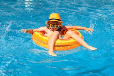 Yüzme havuzunda şişme oyuncak yüzüğü olan küçük bir çocuk. Çocuklar yaz tatilinde yüzerler. Şamandırada çocuk için yüz. Plaj denizi ve su eğlencesi