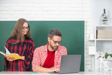 Öğretmen okul çocuğuna dersi açıklıyor. İlkokul öğrencileri öğreniyor. Bilgisayar kullanan okul çocuğu