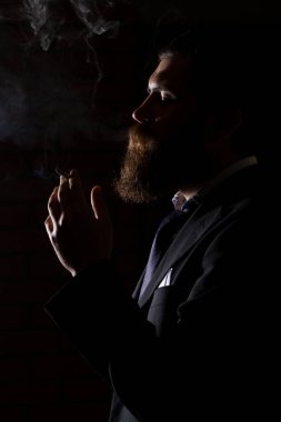 Siyah üzerine izole sigara içen adam. Bir adam elinde esrar, esrar ve çakmak tüttürür. Siyah arka planda duman. Tıbbi marihuana kullanımı ve esrar kullanımının yasallaştırılması kavramları