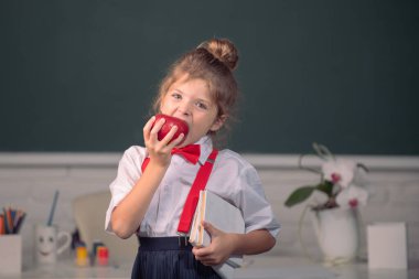 Sınıftaki küçük liseli öğrenci okulda elma yiyor. Okula geri dön.