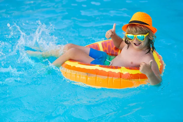 Child in swimming pool with inflatable toy ring. Children summer vacation. Swim for child on float. Beach sea and water fun