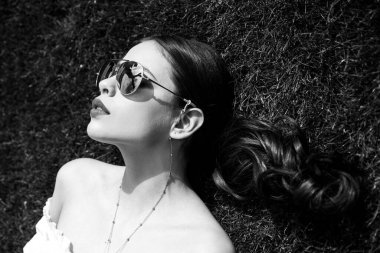 Çimenlerde rahatlayan genç bir kadının portresi. Çimenlerde yatan kadın