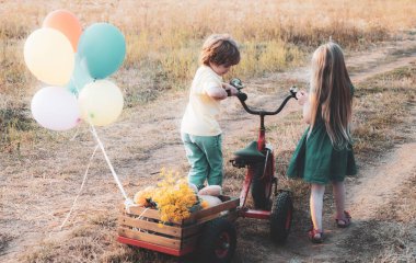 Kız ve erkek kardeşlerin tarlada çalışmalarını arka planda görüyoruz. Kırsal kesimde yaz. Çocuklar çiftlikte eğleniyor