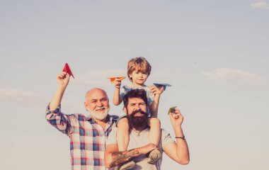 Babalar günün kutlu olsun. Mutlu üç nesil erkekler mavi gökyüzü arka planında eğleniyor ve gülümsüyor. Büyükbaba oyun zamanı. Uçak uçmaya hazır.
