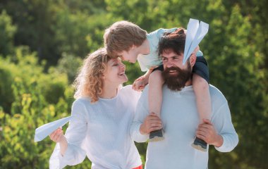 Baba oğlunu parka geri götürüyor. Mutlu aile ve küçük oğlu mavi gökyüzünde oynuyorlar. Çocukluk. Baba, anne ve oğul kamp yapıyor.