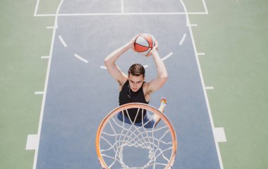 Basketbolcu. Spor ve basketbol. Adam zıplar ve topu sepete atar.