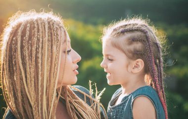 Anne ve kız oynuyorlar ve sarılıyorlar. Saç örüyorum. Örgü ören güzel bir kız çocuğu. Saç örgüsü modaya uygun.