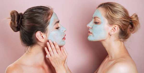Healthy natural tender girls do beauty spa procedures with clay mud mask at face. Happy funny mood. Healthy and wellness concept. Women with bare shoulders do spa procedures