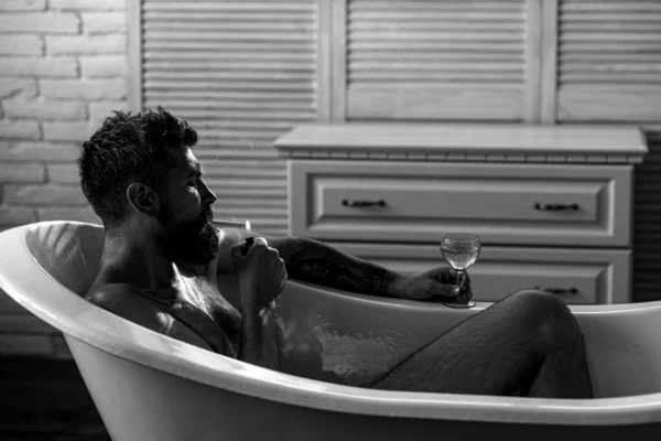 Depression man smoking in bath. Bearded man drinking and smoking in bath. Depression male. Negative emotions