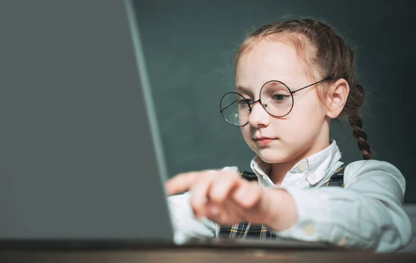 ブラックボードの背景にラップトップコンピュータ上で動作する人形 学校の教室で黒板の近くの子供 子供は黒板を背景に授業で学んでいます — ストック写真