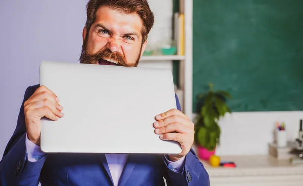 Funny teacher with laptop notebook in classroom at school. Excited teacher professor wearing formal suit with funny expression emotions face