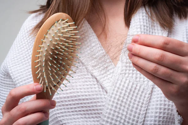 Concept of hair loss. Problem hair in comb, isolated. Damaged unhealthy hair in hand closeup