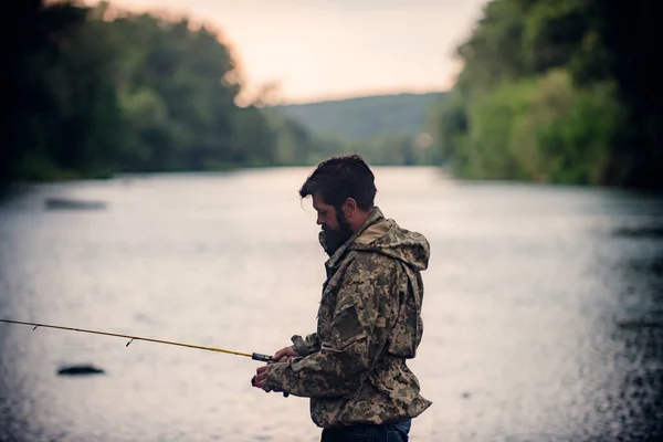 Man with fishing rod, fisherman men in river water outdoor. Spring fishing hobby