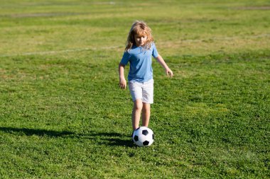 Genç futbolcu. Genç çocuk futbol topunu tekmeliyor. Futbolcu hareket halinde, çocuk hareket halinde. Spor yaparken tatlı bir çocuk.