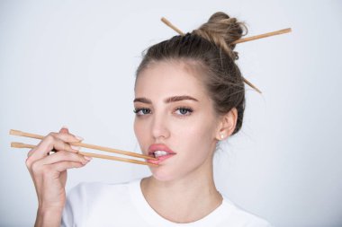 Yemek çubuklarıyla dudak karıştıran seksi bir kız. Sushi reklamı için seksi ağız.