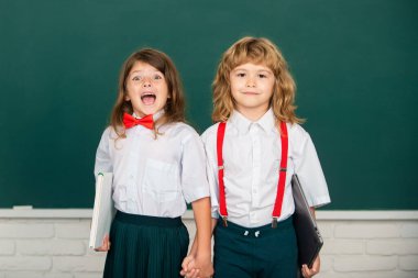 Okula dönelim. Öğrenci arkadaşlar bilgi gününde okula dönüyorlar. En iyi okul arkadaşları tahtanın yanında el ele tutuşuyorlar.