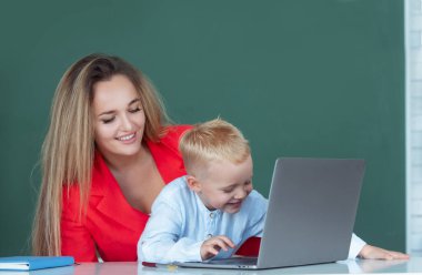 Okul dersinde konuşan öğrenci ve öğretmenin portresi. Anne ve oğlu birlikte bilgisayar laptopu kullanıyorlar. Bilgisayar dersinde ilkokul öğrencilerine yardım eden, dizüstü bilgisayarla öğrenen öğretmen