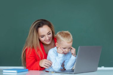 Küçük okul çocuğu internette bilgisayar kullanıyor. Annesiyle birlikte dizüstü bilgisayar kullanıyor. İlkokul öğretmeni ve öğrenci sınıfta.