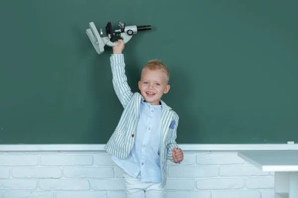 School boy studying math on lesson in classroom at elementary school. Success, motivation, winner, genius concept. Little child with microscope