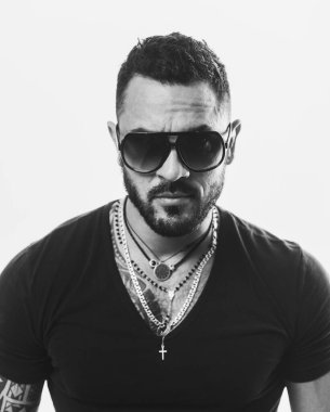 Erkek yüzü. Yakışıklı, erkeksi bir adamın portresi. Gri duvara karşı memnun iş adamının portresi. Güneş gözlüğü. Şehir modası