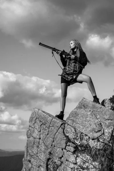 Female with a gun. Woman hunter with a gun. Calibers of hunting rifles. Hunter with a shotgun in a traditional shooting clothing. Outdoors active lifestyle