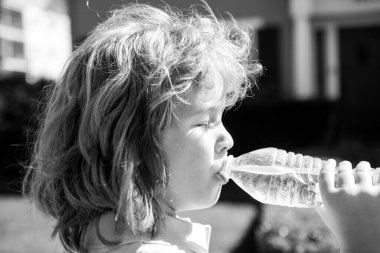 Şişeden su içen sevimli bir çocuğun portresi. Kafkas çocuk yüzünü kapatın. Komik çocuğun yakın plan kafası.