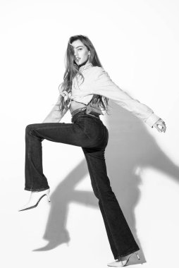 Hareket modeli. Pembe gömlekli ve kot pantolonlu moda kadını. Moda pozu vermiş güzel bir bayan, uzun boylu.