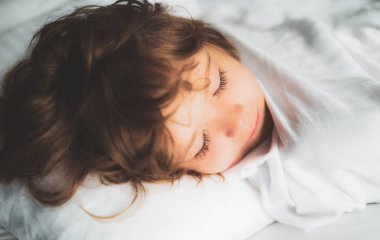 Yumuşak yastıklarda uzanan sakin sevimli çocuklar. Çocuklar uyuyor. Altı yaşındaki çocuk yatakta uyuyor.