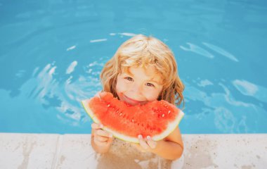 Yaz tatilinde havuzda yüzen karpuzlu bir çocuk. Açık havada karpuz parçaları olan çocuklar. Yaz tatili ve sağlıklı beslenme konsepti