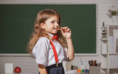 Sınıfta çikolata yiyen, güzel, okul üniformalı bir kızın portresi. İlkokul ve ilköğretim