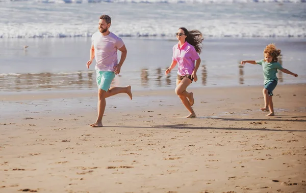 ビーチで走るフィットネスファミリー 子供の息子と幸せな母親の父親は 夏休み中に楽しんでいます 子供と一緒に屋外で家族のジョギング スポーツ 夏の健康 健康的なライフスタイル — ストック写真