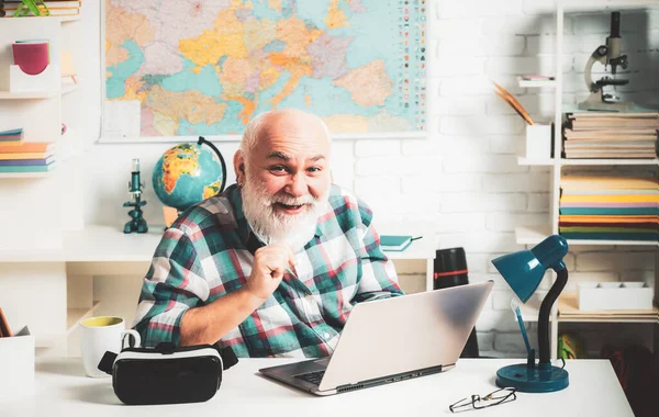 Mature man teacher on balckboard background. Old teacher loves smiles