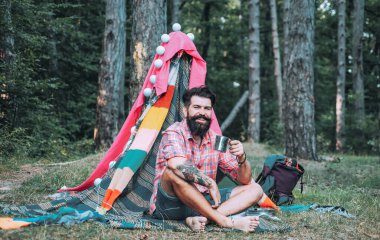 Turizm doğaya dayanıyor. Seyahat eğlence açık hava aktivite konsepti. Dinlenme kampı. Dalların sığınağı. Hovel içinde sakallı adam.