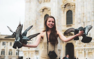 Milano 'daki Duomo Katedrali' nin önündeki mutlu turist. Aralarında güvercin oturan komik kız. Güvercinler kızların elinden besleniyor Milan Katedrali 'nde güvercinlerle tatil konsepti