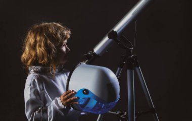 Uzay kasklı ve metal kostümlü bir astronot olmak için oynayan bir çocuk. Siyah kasklı komik çocuk portresi.
