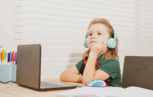 家庭教育の概念 ノートパソコンでオンラインレッスンを見てヘッドセットの学校の少年 — ストック写真